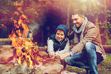 Image showing father and son roasting marshmallow over campfire