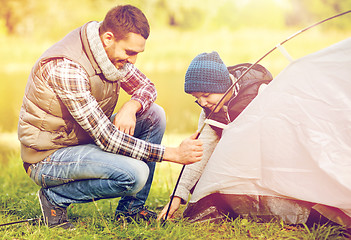 Image showing happy father and son setting up tent outdoors