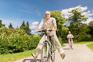 Image showing happy senior couple riding bicycles at summer park