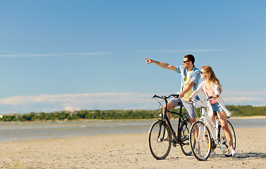 Image showing happy young couple riding bicycles at seaside