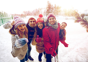 Image showing happy friends with smartphone on ice skating rink