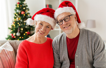 Image showing happy senior couple in santa hats at christmas