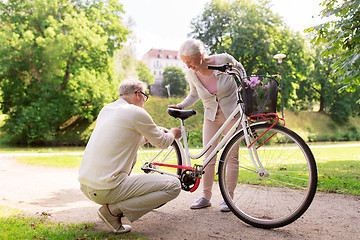 Image showing happy senior couple with bicycle at summer park