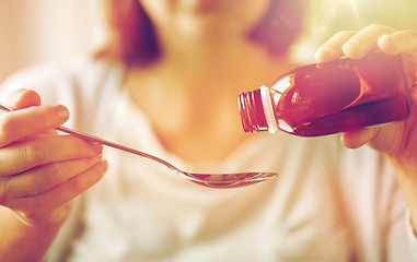 Image showing woman pouring medication from bottle to spoon