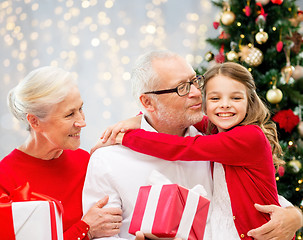 Image showing happy family with christmas gifts over lights