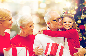 Image showing happy family with christmas gifts over lights