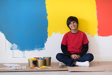 Image showing young boy painter resting after painting the wall