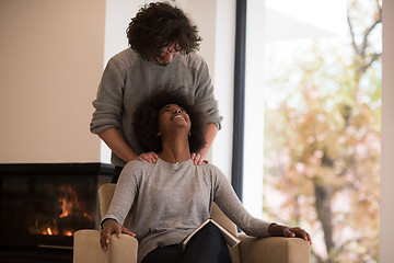 Image showing multiethnic couple hugging in front of fireplace