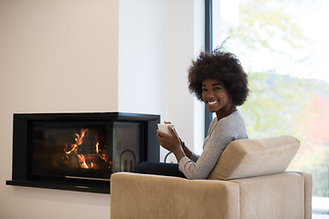 Image showing black woman drinking coffee in front of fireplace