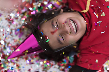 Image showing kid blowing confetti while lying on the floor