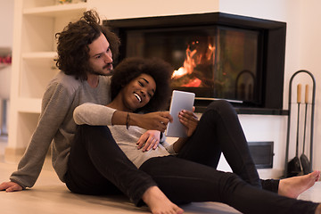 Image showing multiethnic couple using tablet computer on the floor