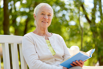 Image showing happy senior woman reading book at summer park