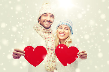 Image showing smiling couple in winter clothes with red hearts