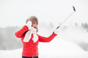 Image showing happy woman with selfie stick outdoors in winter