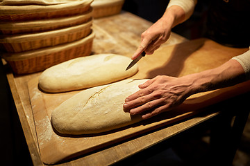 Image showing baker making bread and cutting dough at bakery