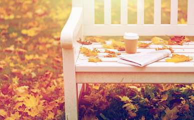 Image showing newspaper and coffee cup on bench in autumn park