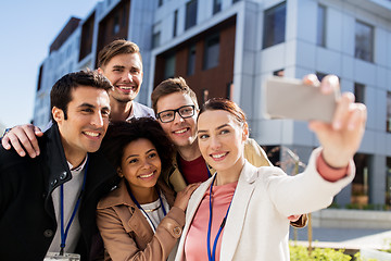 Image showing happy people with conference badges taking selfie