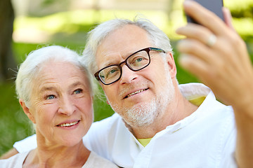 Image showing senior couple with smartphone taking selfie in summer