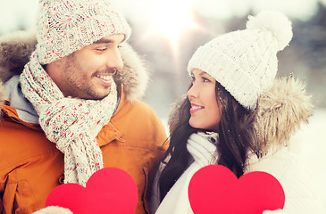 Image showing happy couple with red hearts over winter landscape