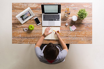 Image showing woman drawing to notebook at home office