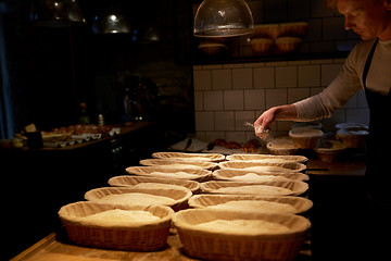 Image showing baker with baskets for dough rising at bakery