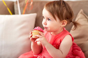 Image showing happy baby girl eating cupcake on birthday party