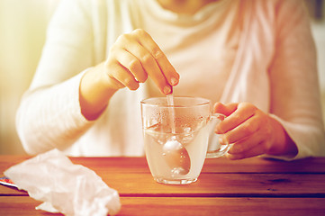 Image showing woman stirring medication in cup with spoon