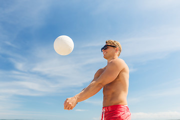 Image showing young man with ball playing volleyball on beach