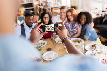 Image showing friends taking picture by smartphone at restaurant