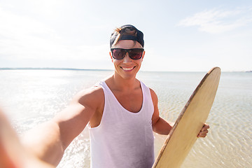 Image showing happy young man with skimboard on summer beach