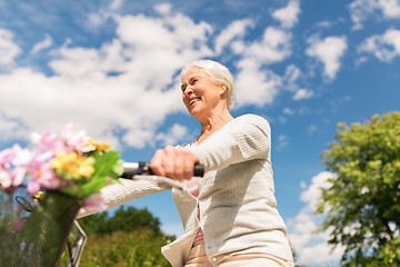 Image showing happy senior woman riding bicycle at summer park