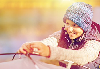 Image showing happy boy setting up tent outdoors