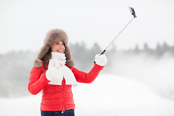 Image showing happy woman with selfie stick outdoors in winter