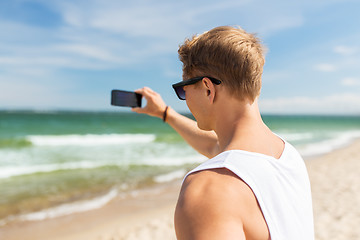 Image showing man with smartphone photographing on summer beach