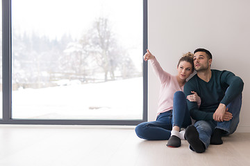 Image showing young couple sitting on the floor near window at home