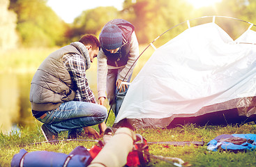 Image showing happy father and son setting up tent outdoors