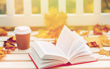 Image showing open book and coffee cup on bench in autumn park