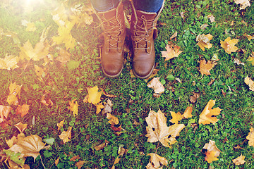 Image showing female feet in boots and autumn leaves on grass