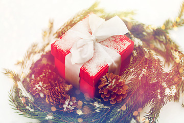 Image showing christmas gift and fir wreath with cones on snow