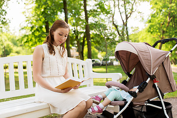 Image showing mother with child in stroller reading book at park