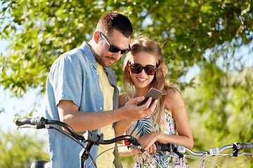 Image showing happy couple with bicycles and smartphone outdoors