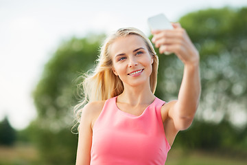 Image showing happy woman taking selfie with smartphone outdoors