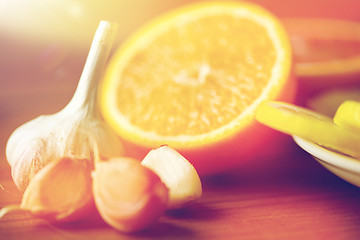 Image showing close up of garlic and orange on wooden table