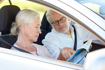 Image showing happy senior couple with map driving in car
