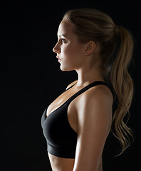 Image showing young woman in black sportswear posing in gym