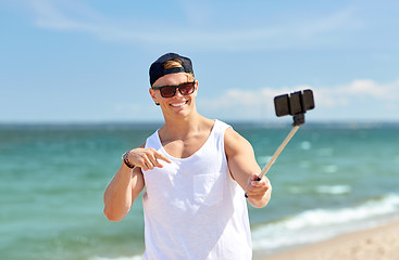 Image showing man with smartphone selfie stick on summer beach