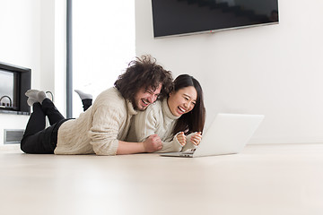 Image showing young multiethnic couple using a laptop on the floor