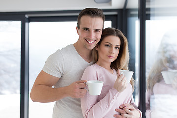 Image showing young couple enjoying morning coffee by the window