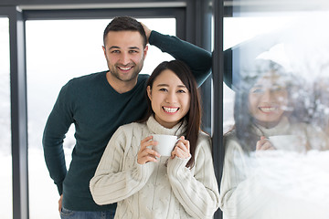 Image showing multiethnic couple enjoying morning coffee by the window