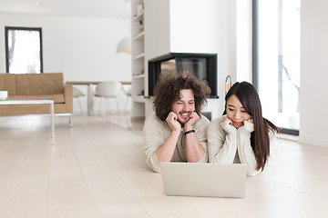 Image showing young multiethnic couple using a laptop on the floor